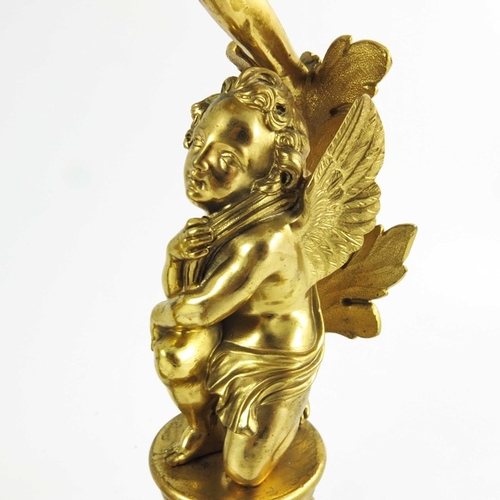 554 - A Pair of 19th Century Gilt Bronze Candlesticks, each modelled with winged cherubs mounted on circul... 