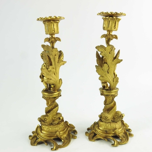 554 - A Pair of 19th Century Gilt Bronze Candlesticks, each modelled with winged cherubs mounted on circul... 