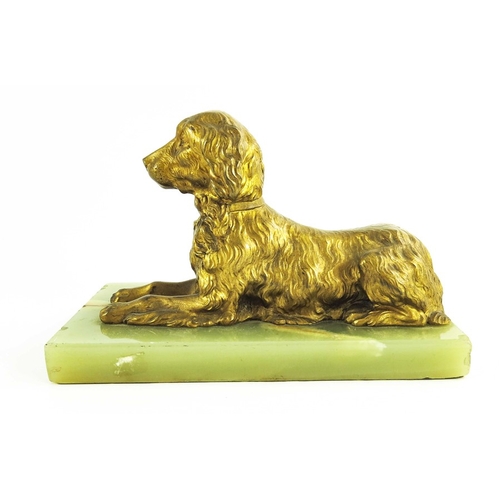 570 - A 19th century gilt bronze figure of a reclining spaniel on a onyx base, 12cm high including base