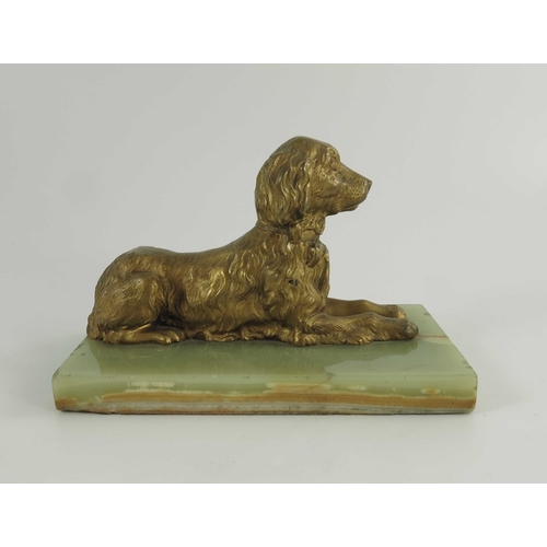 570 - A 19th century gilt bronze figure of a reclining spaniel on a onyx base, 12cm high including base