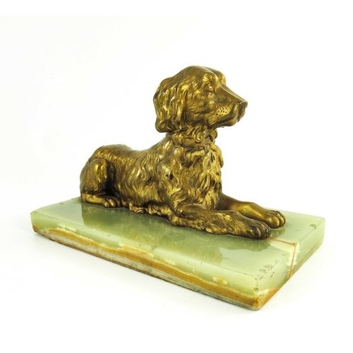 570 - A 19th century gilt bronze figure of a reclining spaniel on a onyx base, 12cm high including base