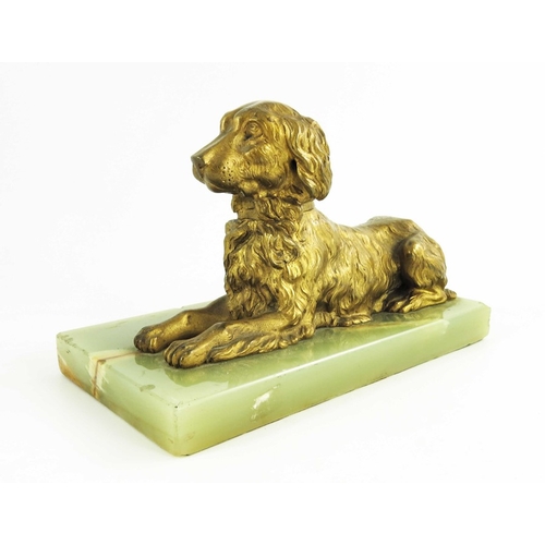 570 - A 19th century gilt bronze figure of a reclining spaniel on a onyx base, 12cm high including base