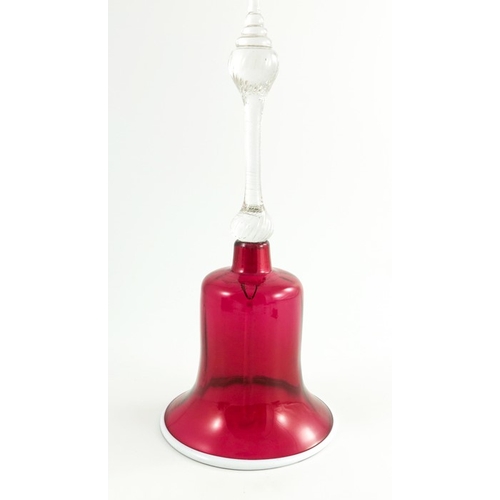 668 - A Victorian cranberry and opaque glass hand bell, the rim edged in white, the handle knopped and twi... 