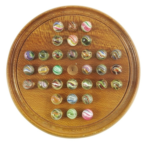 787 - A wooden solitaire board with 32 pontilled swirl marbles, including onionskins, latticinio cores etc... 