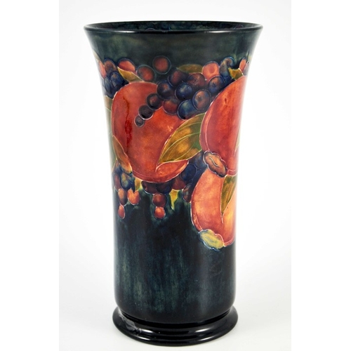 1134 - William Moorcroft, a Pomegranate on ochre and blue vase, circa 1915, cylindrical trumpet form, on fo... 