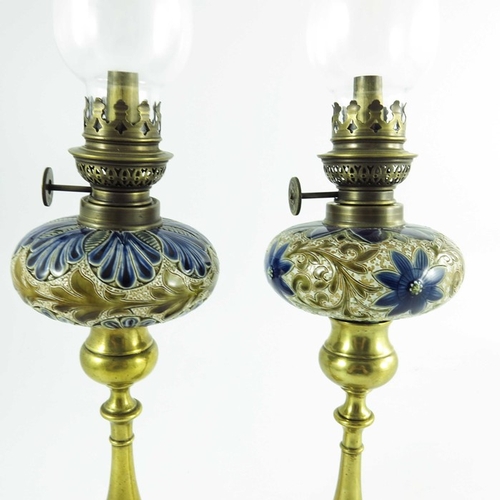 1231 - A pair of Doulton Lambeth stoneware table oil lamps, 1884, squat ovoid reservoirs decorated with fol... 