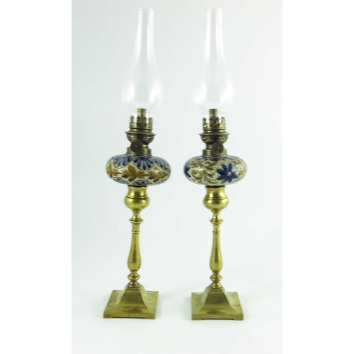 1231 - A pair of Doulton Lambeth stoneware table oil lamps, 1884, squat ovoid reservoirs decorated with fol... 