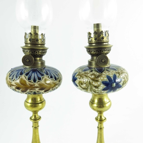 1231 - A pair of Doulton Lambeth stoneware table oil lamps, 1884, squat ovoid reservoirs decorated with fol... 