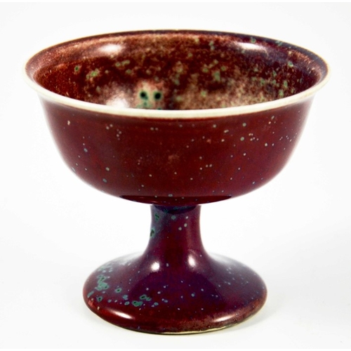 1341 - A Ruskin high fired Melba cup, circa 1920, pedestal ogee form, red with speckled purple and green, i... 