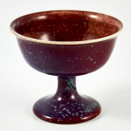 1341 - A Ruskin high fired Melba cup, circa 1920, pedestal ogee form, red with speckled purple and green, i... 