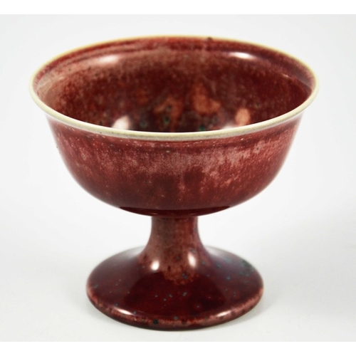 1350 - A Ruskin high fired Melba cup, circa 1920, pedestal ogee form, red with speckled purple and green, i... 