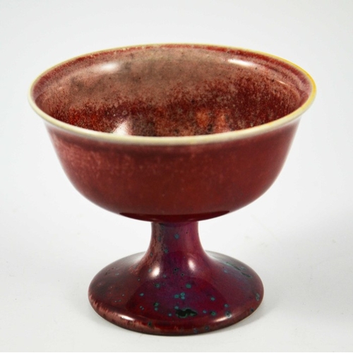 1350 - A Ruskin high fired Melba cup, circa 1920, pedestal ogee form, red with speckled purple and green, i... 