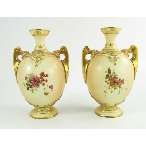 1450 - A pair of Royal Worcester blush ivory ground two handle vases, florally decorated to two sides in co... 