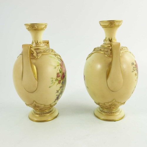 1450 - A pair of Royal Worcester blush ivory ground two handle vases, florally decorated to two sides in co... 