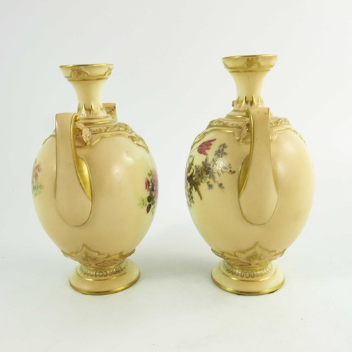 1450 - A pair of Royal Worcester blush ivory ground two handle vases, florally decorated to two sides in co... 