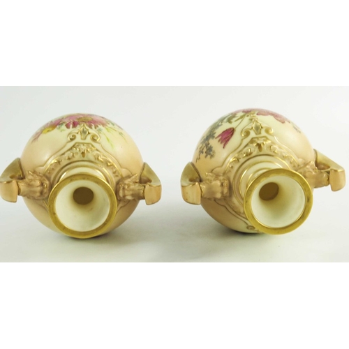 1450 - A pair of Royal Worcester blush ivory ground two handle vases, florally decorated to two sides in co... 