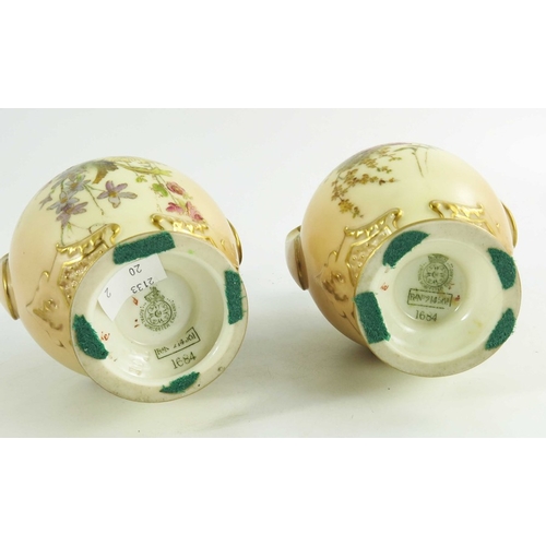 1450 - A pair of Royal Worcester blush ivory ground two handle vases, florally decorated to two sides in co... 