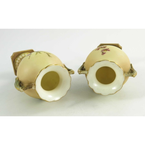 1460 - A pair of Royal Worcester miniature blush ivory ground two handled vases, florally decorated with th... 