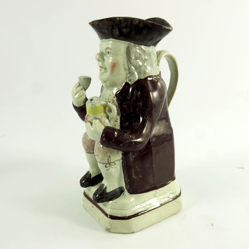 1536 - A small Staffordshire Toby jug, circa 1820, polychrome decorated, modelled with jug and beaker, 18cm... 