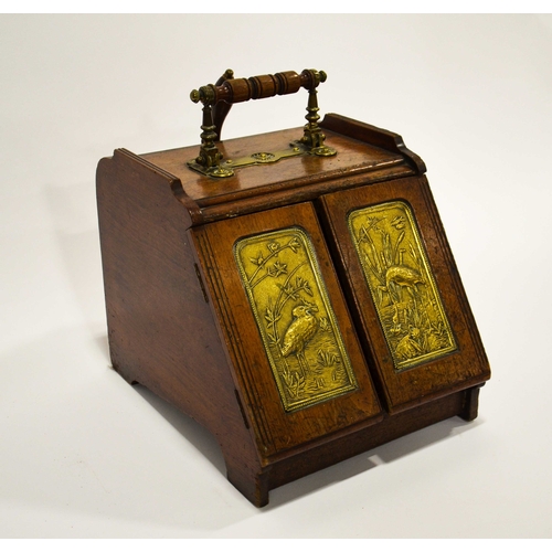 555 - An Aesthetic Movement walnut and brass panelled mechanical coal scuttle, the twin doors opening with... 