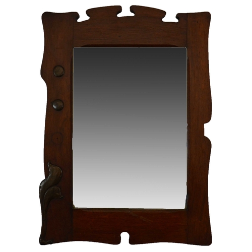 581 - An Arts and Crafts walnut and patinated copper mirror, asymetrical fretted with applied planished ro... 