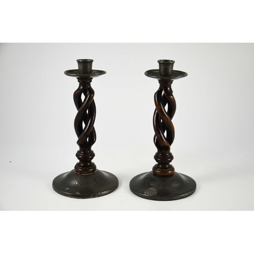 617 - Liberty and Co., pair of Tudric pewter and oak candlesticks, model 01298, open barley twist with pla... 