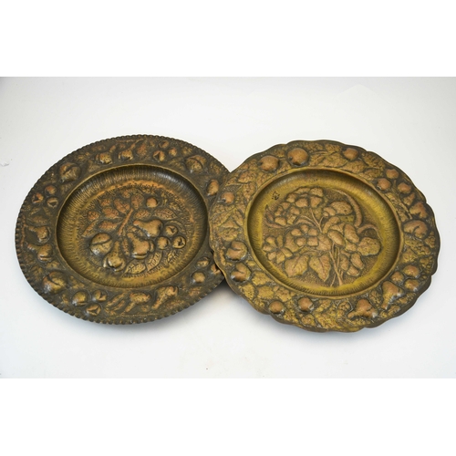 626 - A matched pair of Arts and Crafts repousse copper chargers, each decorated with a central floral spe... 