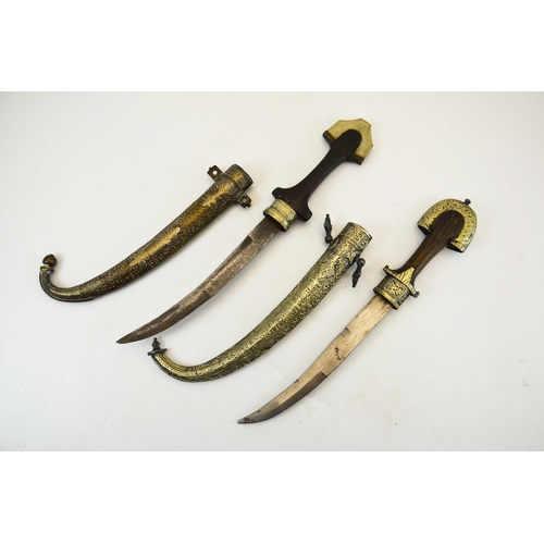 628 - Two Arabic Jambiya daggers, housed in gilt metal scabbards, wooden grips, 41cm long (2)