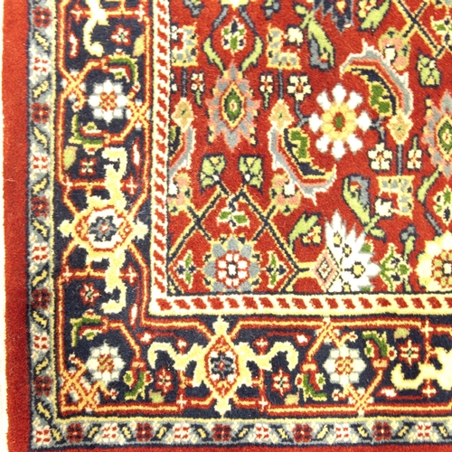 518 - A Persian style deep red ground corridor runner, 20th century, with all over stylised flower head de... 