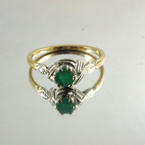 120 - An 18ct yellow gold ring inset with circular emerald in white metal decorative mount, stamped