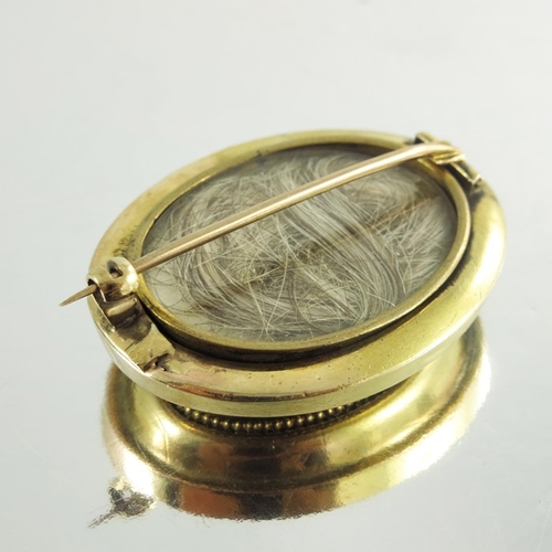 146 - A Victorian yellow gold oval mourning brooch, engraved with bird and branches on stepped moulded bod... 