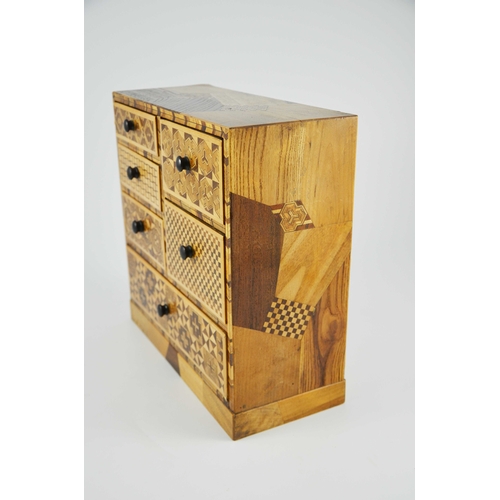 475 - A Japanese Hakone parquetry small chest of five short over one long drawers, each with different geo... 