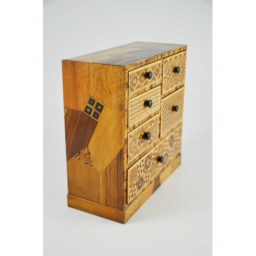 475 - A Japanese Hakone parquetry small chest of five short over one long drawers, each with different geo... 