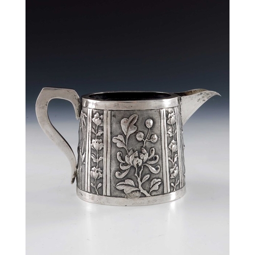 7 - A Chinese export silver jug, circa 1890, conical oval form, repousse embossed with panels of prunus ... 