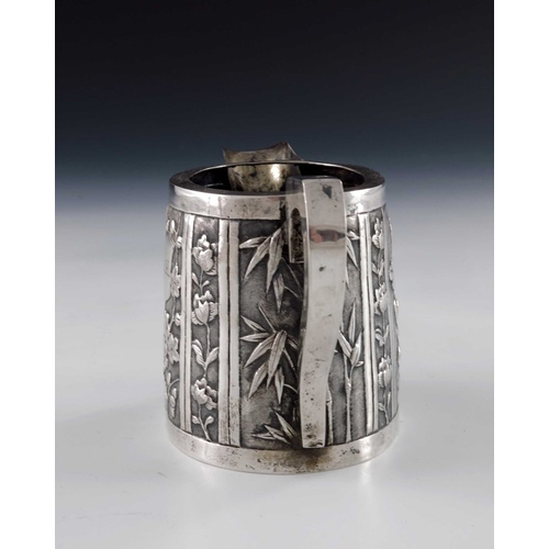 7 - A Chinese export silver jug, circa 1890, conical oval form, repousse embossed with panels of prunus ... 