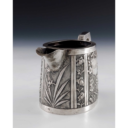 7 - A Chinese export silver jug, circa 1890, conical oval form, repousse embossed with panels of prunus ... 