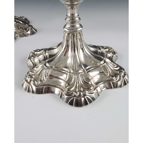 42 - A pair of cast Continental silver candlesticks, 18th century, the stepped petal bases with moulded f... 