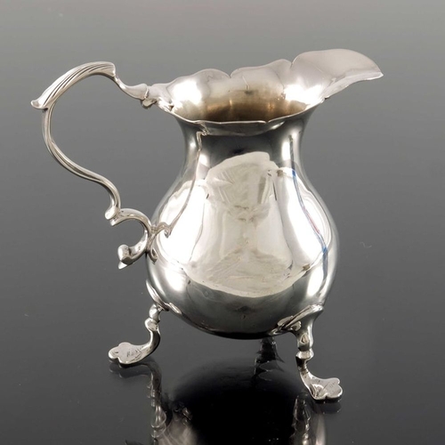 143 - A George II silver jug, London 1750, baluster form with ogee rim and S C scroll handle, on three tre... 