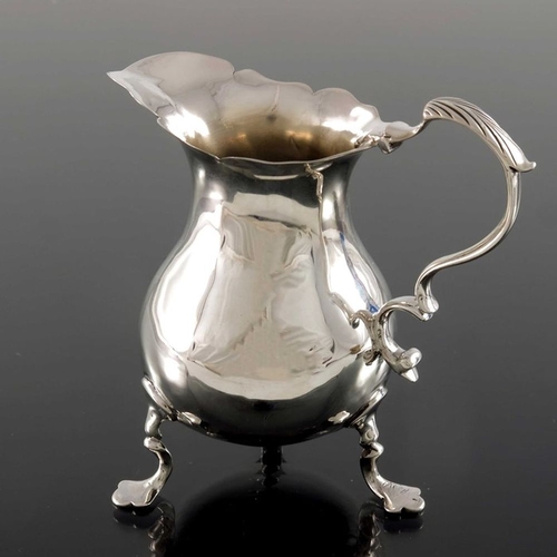 143 - A George II silver jug, London 1750, baluster form with ogee rim and S C scroll handle, on three tre... 