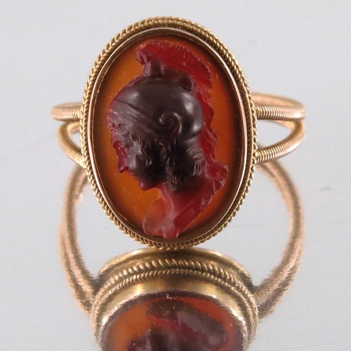 268 - A Revivalist yellow metal and carved carnelian ring, in the style of Castellani, the central stone m... 