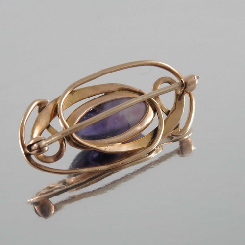 273 - Archibald Knox for Liberty and Co., an Arts and Crafts amethyst and gold brooch, the central cabocho... 