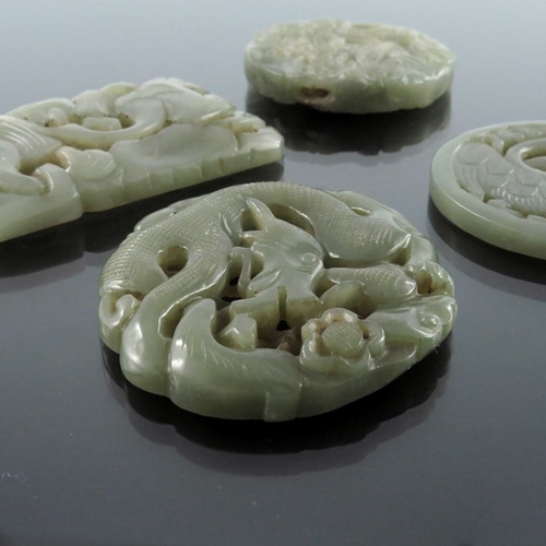 413 - Four Chinese reticulated carved jade pendants, including circular coiled dragon, goose and foliate s... 