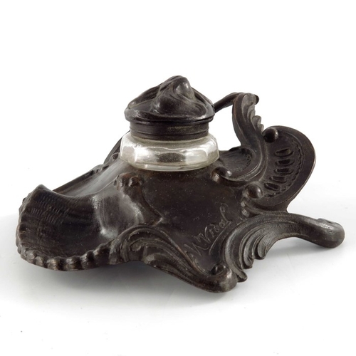 493 - N Vidal, an Art Nouveau bronzed inkwell, cast in relief with foliate scrolls and shells, faceted gla... 