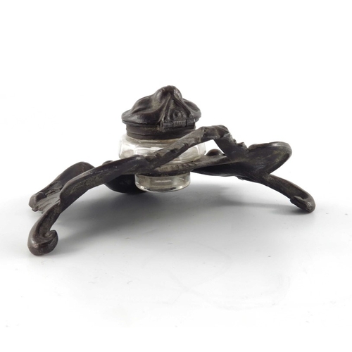 493 - N Vidal, an Art Nouveau bronzed inkwell, cast in relief with foliate scrolls and shells, faceted gla... 