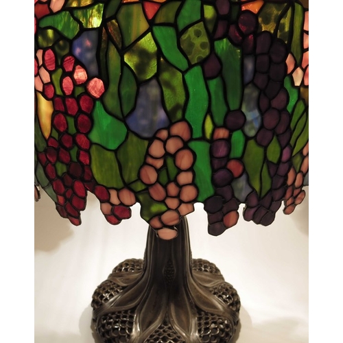 530 - A bronze and stained glass table lamp, in the style of Tiffany, the reticulated foliate and fish sca... 