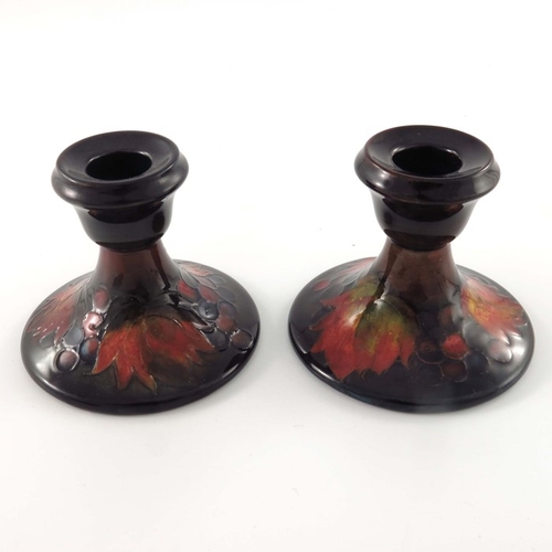 646 - William Moorcroft, a pair of Flambe Leaf and Berry candlesticks, circa 1935, splayed form with ogee ... 