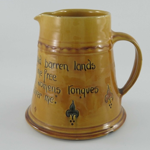 653 - C H Brannam for Liberty and Co., an art pottery motto jug, circa 1915, treacle glazed conical form, ... 