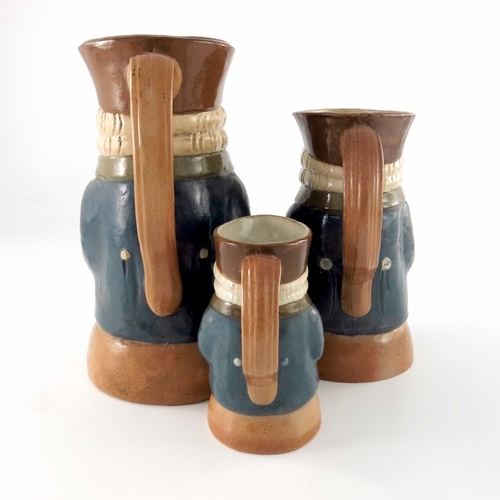 668 - Harry Simeon for Doulton Lambeth, a graduated set of three Toby jugs, each modelled with bottle and ... 