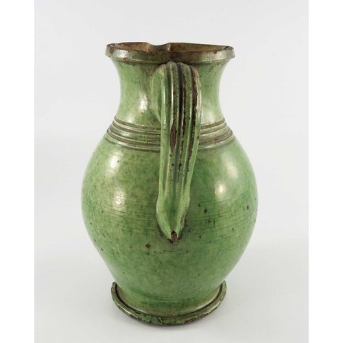 771 - A 19th century green glazed earthenware jug, possibly Farnham, ovoid form, incised to the shoulder w... 