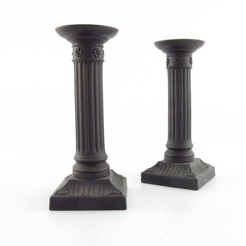 772 - A pair of Wedgwood black basalt candlesticks, circa 1820, fluted column form, on square bases, the c... 